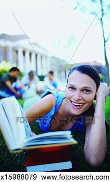 Stock Photograph - close-up of young 
woman lying on 
grass reading 
book with three 
other. fotosearch 
- search stock 
photos, pictures, 
images, and photo 
clipart