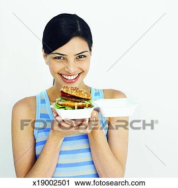 Stock Photography - front view of 
young woman holding 
burger. fotosearch 
- search stock 
photos, pictures, 
images, and photo 
clipart