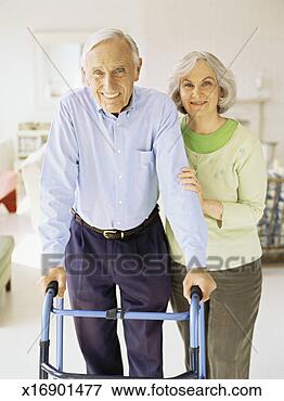 Picture - portrait of a 
senior woman helping 
a senior man to 
walk with a walker. 
fotosearch - search 
stock photos, 
pictures, images, 
and photo clipart