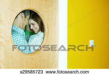Stock Photo - young couple face 
to face, smiling, 
view through round 
window. fotosearch 
- search stock 
photos, pictures, 
images, and photo 
clipart