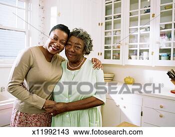 Stock Photo - woman and mature 
woman hugging 
in the kitchen. 
fotosearch - search 
stock photos, 
pictures, images, 
and photo clipart