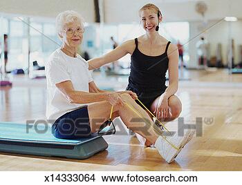 Stock Photo - female fitness 
instructor assisting 
elderly woman 
in health club. 
fotosearch - search 
stock photos, 
pictures, images, 
and photo clipart