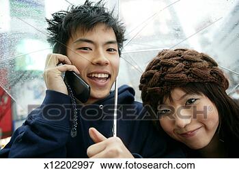 Picture - teen couple (16-18) 
under umbrella, 
boy using mobile 
phone, close up. 
fotosearch - search 
stock photos, 
pictures, images, 
and photo clipart