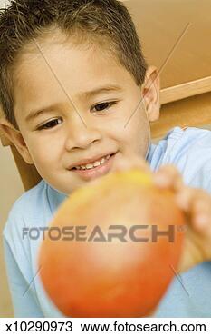 Stock Photo - smiling boy holding 
mango, close-up, 
selective focus, 
focus on boy. 
fotosearch - search 
stock photos, 
pictures, images, 
and photo clipart