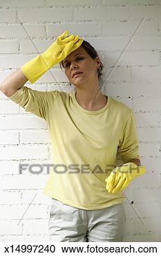 Stock Photography - woman with rubber 
gloves standing 
against wall and 
wiping forehead. 
fotosearch - search 
stock photos, 
pictures, images, 
and photo clipart