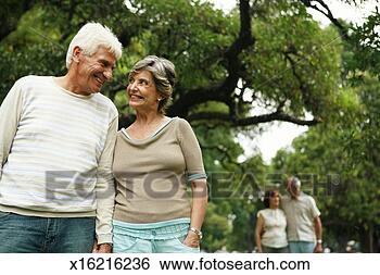 Stock Photo - senior couple 
in park, smiling, 
mature couple 
in background. 
fotosearch - search 
stock photos, 
pictures, images, 
and photo clipart
