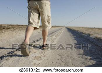 Stock Image - man walking along 
dirt track, low 
section, rear 
view, (blurred 
motion). fotosearch 
- search stock 
photos, pictures, 
images, and photo 
clipart