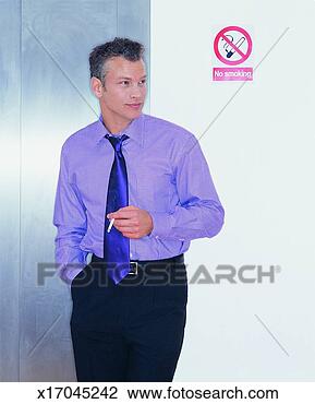 Stock Photo - young businessman 
smoking a cigarette 
next to a no smoking 
sign. fotosearch 
- search stock 
photos, pictures, 
images, and photo 
clipart