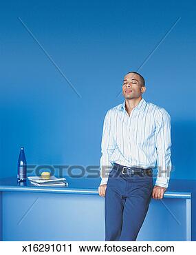 Stock Photography - serene, young 
businessman leaning 
against a table 
with his eyes 
closed. fotosearch 
- search stock 
photos, pictures, 
images, and photo 
clipart