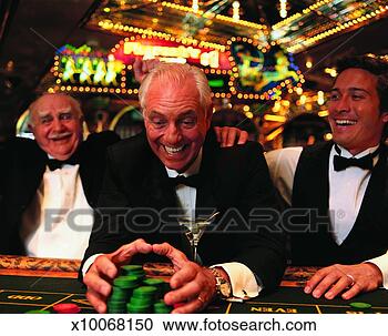 Stock Photography - mature man wearing 
a dinner jacket 
reaching for a 
stack of gambling. 
fotosearch - search 
stock photos, 
pictures, images, 
and photo clipart