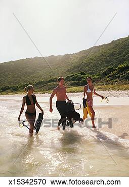 Stock Photography - three young people 
carrying scuba 
diving equipment 
on a beach. fotosearch 
- search stock 
photos, pictures, 
images, and photo 
clipart