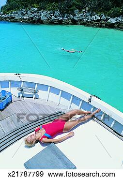 Stock Photograph - young woman sunbathing 
in her swimming 
costume at the 
stern of a ship. 
fotosearch - search 
stock photos, 
pictures, images, 
and photo clipart
