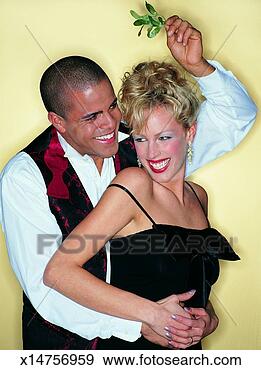 Stock Photograph - smiling man standing 
with his arms 
around a woman 
holding mistletoe. 
fotosearch - search 
stock photos, 
pictures, images, 
and photo clipart
