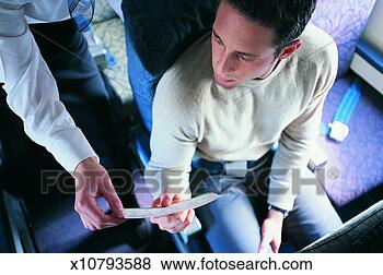 Stock Photo - male passenger 
showing his ticket 
to an air stewardess 
on an aeroplane. 
fotosearch - search 
stock photos, 
pictures, images, 
and photo clipart