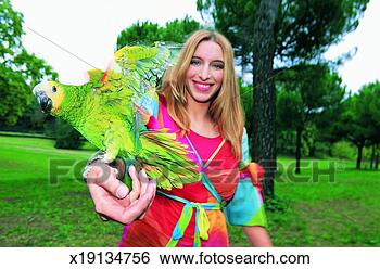 Stock Photo - portrait of a 
woman holding 
a parrot in the 
park. fotosearch 
- search stock 
photos, pictures, 
images, and photo 
clipart