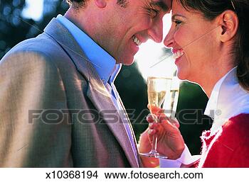 Stock Photo - couple holding 
glasses of champagne 
and standing face 
to face. fotosearch 
- search stock 
photos, pictures, 
images, and photo 
clipart