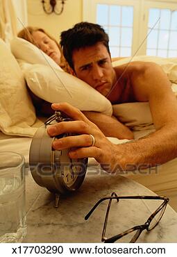 Stock Photography - man frowning as 
he turns off  
the alarm clock. 
fotosearch - search 
stock photos, 
pictures, images, 
and photo clipart