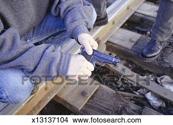 Stock Photo - teenagers (16-17) 
examining gun, 
close-up of gun 
in hands, close-up. 
fotosearch - search 
stock photos, 
pictures, images, 
and photo clipart