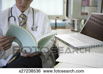 Stock Photo - doctor reading 
medical records 
beside laptop 
(cropped). fotosearch 
- search stock 
photos, pictures, 
images, and photo 
clipart