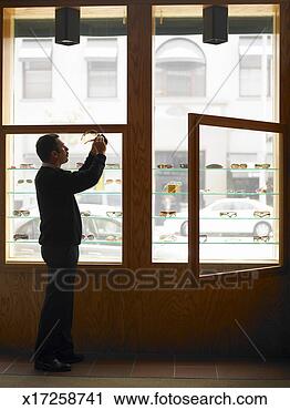 Stock Photography - man cleaning and 
examining eyeglasses 
by window display 
in eyeglass. fotosearch 
- search stock 
photos, pictures, 
images, and photo 
clipart