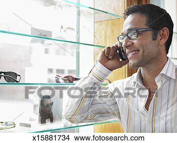 Stock Photo - man using mobile 
phone while standing 
by window display 
in eyeglass. fotosearch 
- search stock 
photos, pictures, 
images, and photo 
clipart