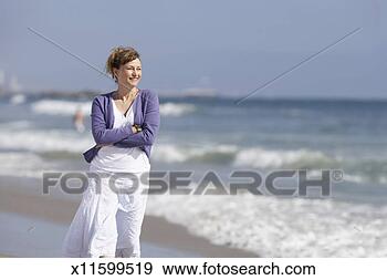 Stock Photograph - mature woman walking 
on beach. fotosearch 
- search stock 
photos, pictures, 
images, and photo 
clipart