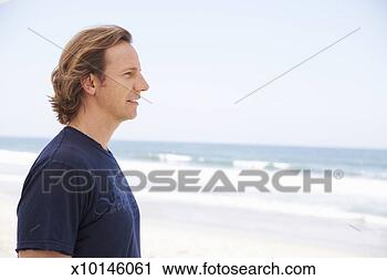 Stock Photography - mid adult man 
on beach, facing 
ocean, profile, 
upper half. fotosearch 
- search stock 
photos, pictures, 
images, and photo 
clipart