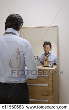 Stock Photo - young man adjusting 
tie in mirror, 
iron stain on 
shirt, rear view. 
fotosearch - search 
stock photos, 
pictures, images, 
and photo clipart