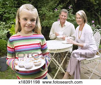 Stock Photo - young girl in 
a garden holding 
a plate full of 
cup cakes with 
two. fotosearch 
- search stock 
photos, pictures, 
images, and photo 
clipart