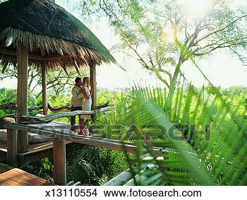 Stock Photo - couple standing 
in a holiday home 
enjoying the view 
over the jungle. 
fotosearch - search 
stock photos, 
pictures, images, 
and photo clipart