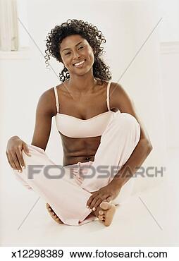 Stock Photograph - woman sitting 
cross-legged in 
tracksuit bottoms 
and a bra,  smiling. 
fotosearch - search 
stock photos, 
pictures, images, 
and photo clipart