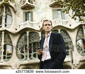 Stock Photograph - businessman stands 
in front of a 
gaudi building 
in barcelona, 
 using. fotosearch 
- search stock 
photos, pictures, 
images, and photo 
clipart
