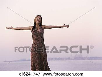 Picture - carefree woman 
in a summer dress 
stands by the 
coast,  her arms. 
fotosearch - search 
stock photos, 
pictures, images, 
and photo clipart