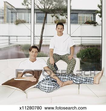 Stock Photography - portrait of a 
gay couple relaxing 
on their sofa. 
fotosearch - search 
stock photos, 
pictures, images, 
and photo clipart