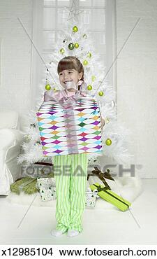Stock Photo - portrait of a 
young girl holding 
a christmas present 
in front of an. 
fotosearch - search 
stock photos, 
pictures, images, 
and photo clipart