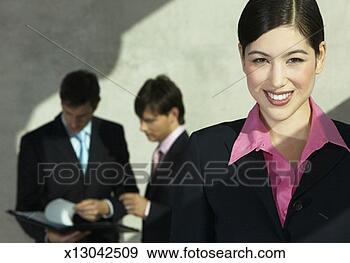Stock Photograph - smiling businesswoman 
looking at the 
camera,  with 
two businessmen 
in. fotosearch 
- search stock 
photos, pictures, 
images, and photo 
clipart