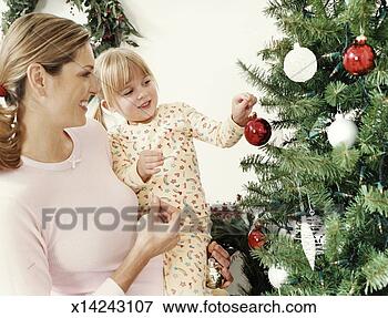 Picture - mother carrying 
her daughter who 
is attaching a 
christmas ornament 
to. fotosearch 
- search stock 
photos, pictures, 
images, and photo 
clipart