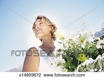 Stock Photo - low angle tilted 
shot of a serene 
bride holding 
a bouquet of white. 
fotosearch - search 
stock photos, 
pictures, images, 
and photo clipart