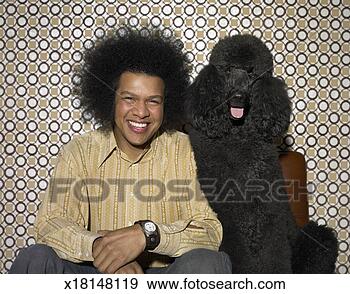 Stock Photograph - man with an afro 
sitting next to 
a black poodle. 
fotosearch - search 
stock photos, 
pictures, images, 
and photo clipart