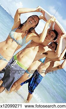 Stock Photography - four teenage friends 
stand in the sea 
in a line carrying 
a surfboard. fotosearch 
- search stock 
photos, pictures, 
images, and photo 
clipart