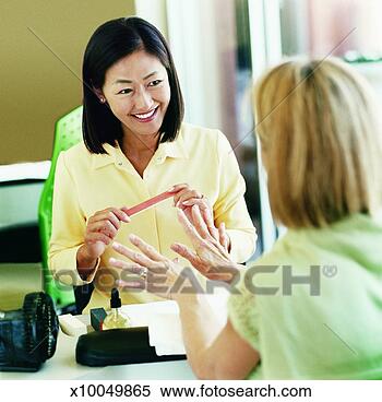 Stock Image - woman in a beauty 
salon having a 
nail manicure 
from a beautician. 
fotosearch - search 
stock photos, 
pictures, images, 
and photo clipart