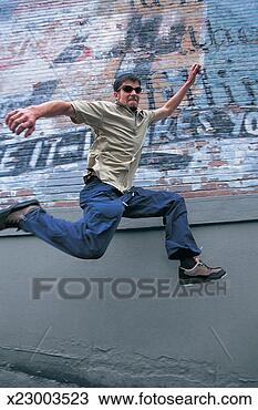 Stock Photo - young man jumping 
in mid air with 
graffiti on a 
brick wall in 
the. fotosearch 
- search stock 
photos, pictures, 
images, and photo 
clipart