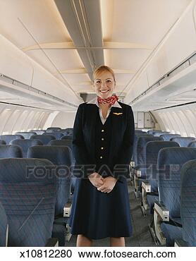 Stock Photography - female flight 
attendant standing 
in the centre 
of a plane cabin. 
fotosearch - search 
stock photos, 
pictures, images, 
and photo clipart