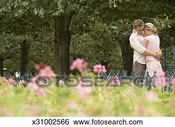 Stock Photo - couple standing 
in park embracing 
(focus on couple). 
fotosearch - search 
stock photos, 
pictures, images, 
and photo clipart