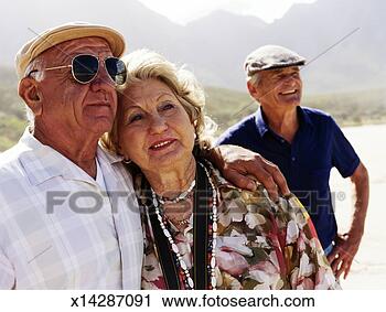 Stock Photography - senior couple 
embracing outdoors, 
senior man smiling 
in background. 
fotosearch - search 
stock photos, 
pictures, images, 
and photo clipart