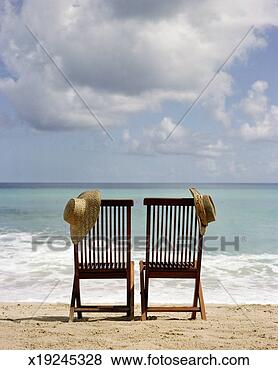 Stock Photo - two chairs on 
beach, straw hats 
hanging on backs, 
rear view. fotosearch 
- search stock 
photos, pictures, 
images, and photo 
clipart