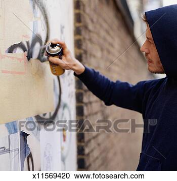 Stock Photography - young man wearing 
hooded top, spraying 
graffiti on wall, 
side view. fotosearch 
- search stock 
photos, pictures, 
images, and photo 
clipart