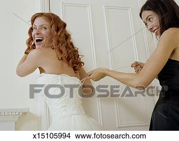Stock Photo - bride having wedding 
dress laced up 
by young woman, 
smiling. fotosearch 
- search stock 
photos, pictures, 
images, and photo 
clipart