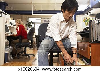 Stock Photo - male office worker 
looking in draw, 
female office 
worker in background. 
fotosearch - search 
stock photos, 
pictures, images, 
and photo clipart
