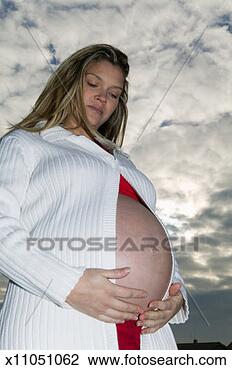 Stock Photo - pregnant young woman holding bulge, outdoors, low angle view. fotosearch - search stock photos, pictures, images, and photo clipart
